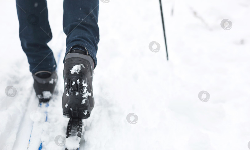 Скачать Ноги лыжника в лыжных ботинках на беговых лыжах. Прогулки по снегу, зимние виды спорта, здоровый образ жизни. Крупный план, копировальное пространство фотосток Ozero