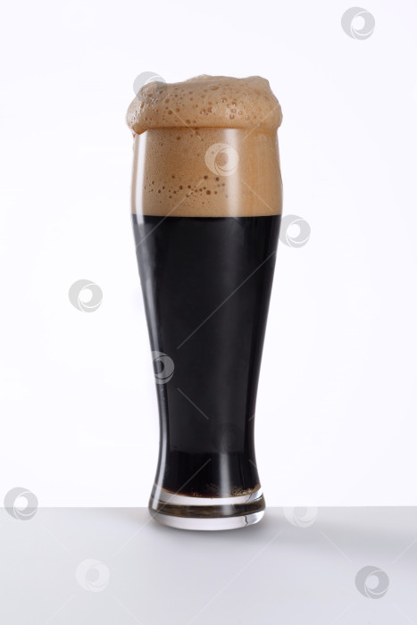 Скачать Бокал свежего и холодного темного пива на серо-коричневом и белом фоне. фотосток Ozero