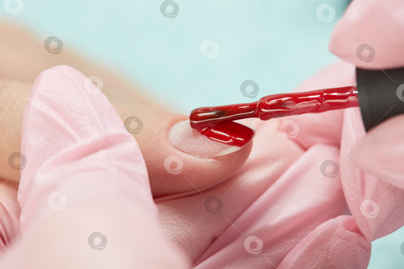 Скачать Косметолог наносит красный лак на женский ноготь. фотосток Ozero