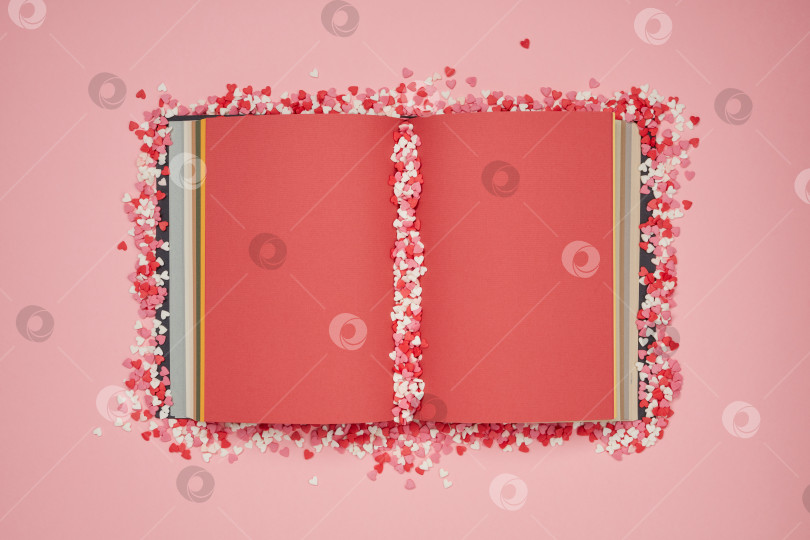 Скачать Конфетные сердечки пастельных тонов на красных книжных страницах и розовом фоне фотосток Ozero