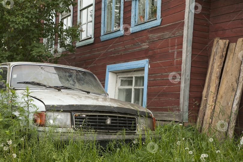 Скачать Старая ржавая машина во дворе деревенского дома в зеленой траве фотосток Ozero