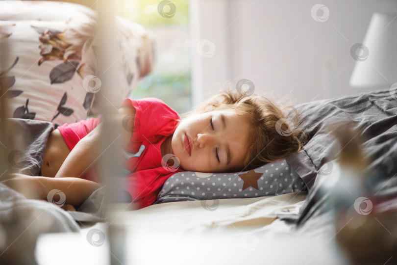Скачать Маленький ребенок сладко спит в своей кроватке. Здоровый сон девочки, вентиляция. Утро, просыпаюсь, солнечный свет льется из окна. Ранний подъем в детский сад, школу. фотосток Ozero