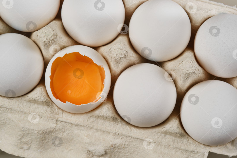 Скачать Белые яйца, целые и разбитые яйца с желтком в картонной упаковке. фотосток Ozero
