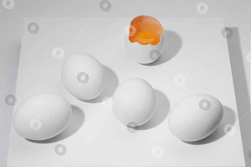 Скачать Белые цельные яйца и разбитое яйцо с желтком на белом фоне. фотосток Ozero