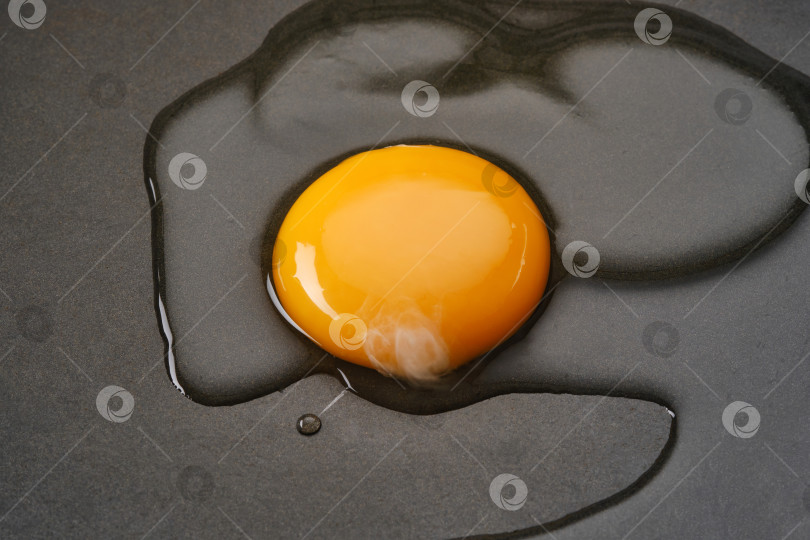 Скачать Разбейте яичный желток и белок на черную поверхность сковороды. фотосток Ozero