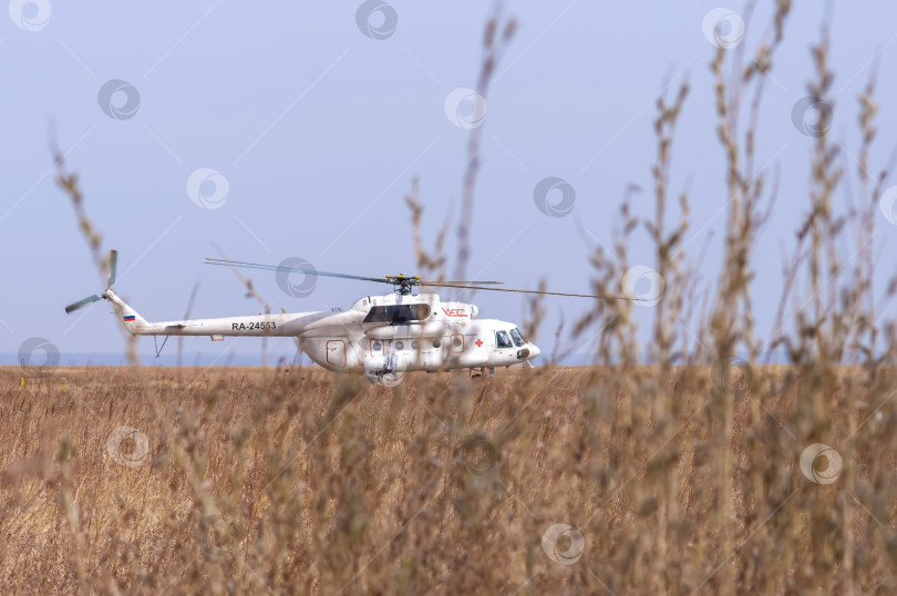 Скачать Белый вертолет Ми-8 с красным крестом стоит на поле с сухой травой. Санитарная авиация. Министерство по чрезвычайным ситуациям фотосток Ozero