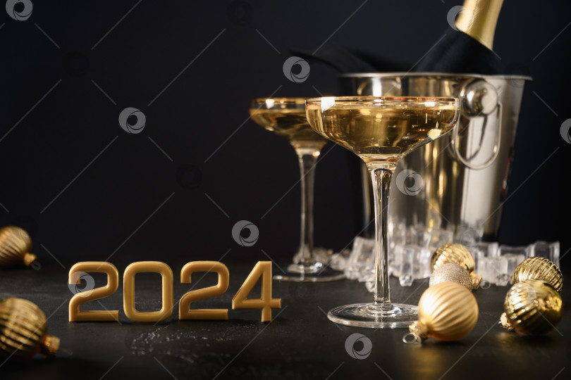 Скачать Новогоднее шампанское в фужерах и бутылка в ведерке украшены рождественскими золотыми безделушками. фотосток Ozero
