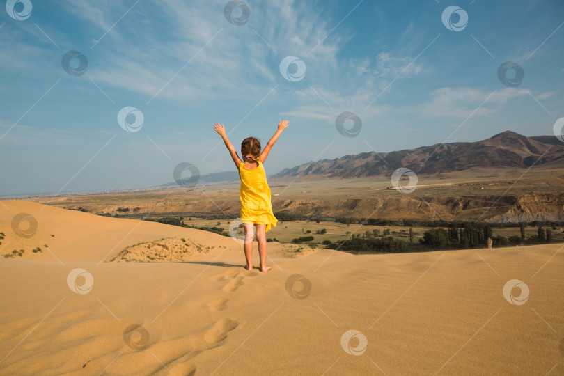 Скачать Девушка-туристка в желтом платье бежит по песчаной дюне в пустыне. Путешествия, достопримечательности Дагестана, дюна Сарыкум фотосток Ozero