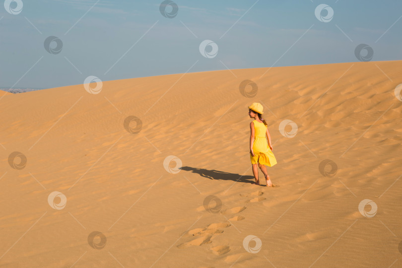 Скачать Девушка-туристка в желтом платье бежит по песчаной дюне в пустыне. Путешествия, достопримечательности Дагестана, дюна Сарыкум фотосток Ozero