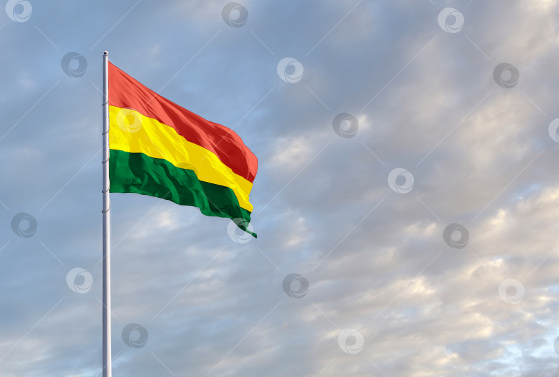 Скачать Развевающийся боливийский флаг на фоне голубого неба с облаками и пустым пространством для текста. фотосток Ozero