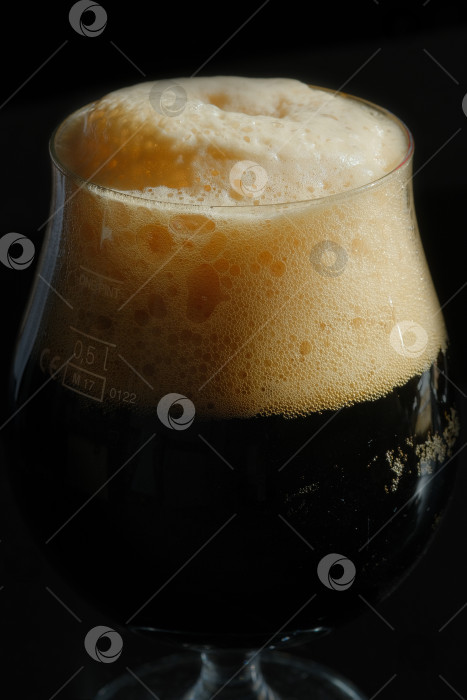 Скачать Полный бокал с темным пивом и пеной на черном фоне. фотосток Ozero