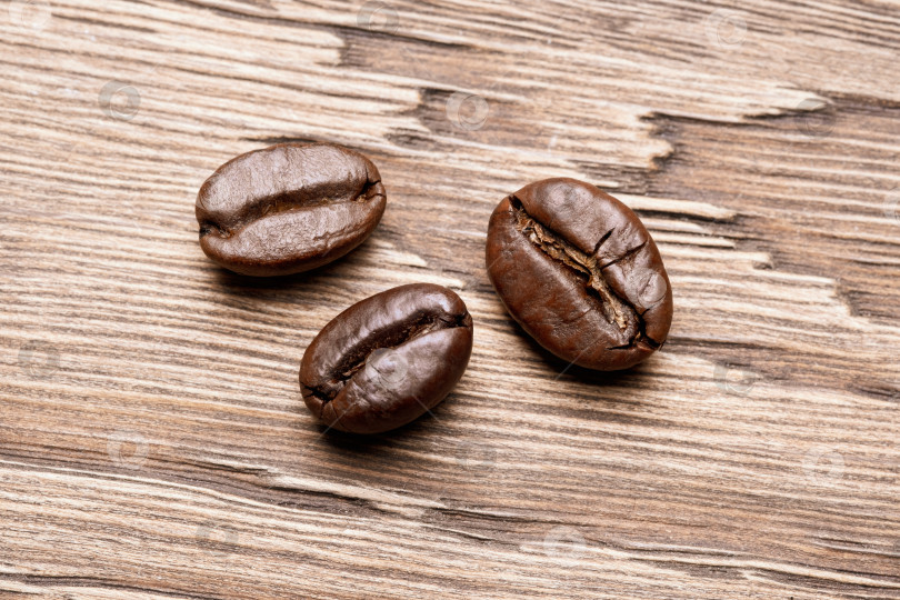 Скачать Макрос трех кофейных зерен на деревянном фоне. фотосток Ozero