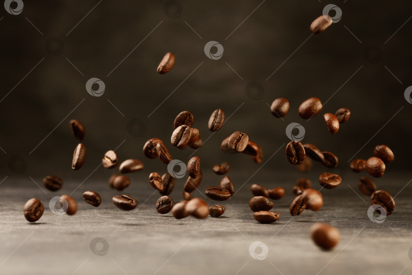 Скачать Зерна обжаренного кофе падают на фоне серого камня. фотосток Ozero