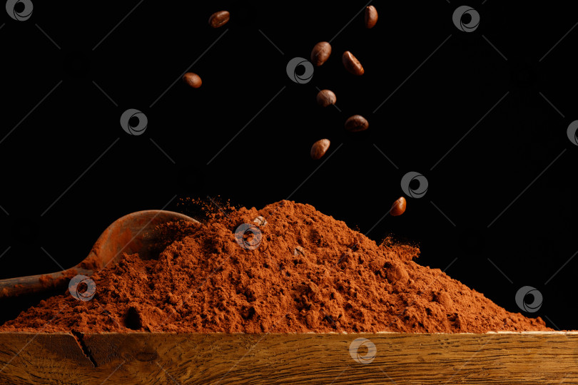 Скачать Падающие кофейные зерна на кучку шоколадной пудры на деревянном столе. фотосток Ozero