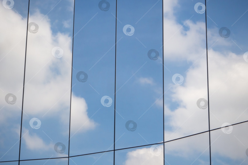 Скачать Отражение облаков и голубого неба на поверхности стеклянной стены современного здания в вертикальной раме фотосток Ozero