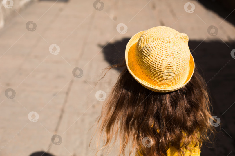 Скачать Девушка-туристка в желтой шляпке и сарафане прогуливается по каменной улице старого города с крепостью. Тур по достопримечательностям. Ребенок заблудился, разыскивая родителей фотосток Ozero