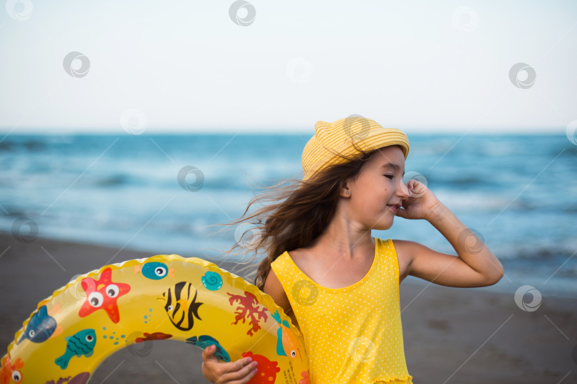 Скачать Девушка с желтым надувным кругом на берегу моря. Отдых на пляже, летние путешествия. фотосток Ozero