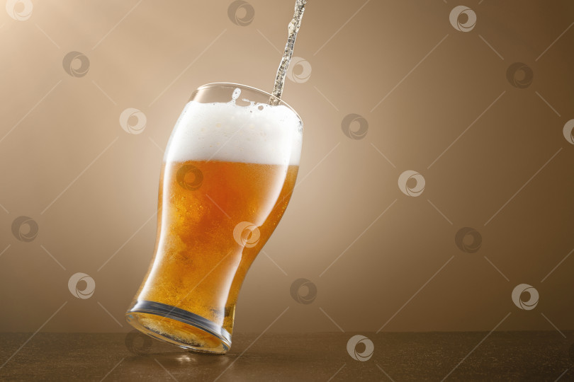 Скачать Струйка разливного пива в бокале на бежевом фоне. фотосток Ozero