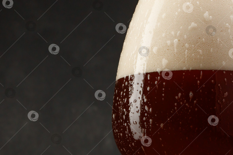 Скачать Деталь бокала с полным пивом на темном фоне. фотосток Ozero