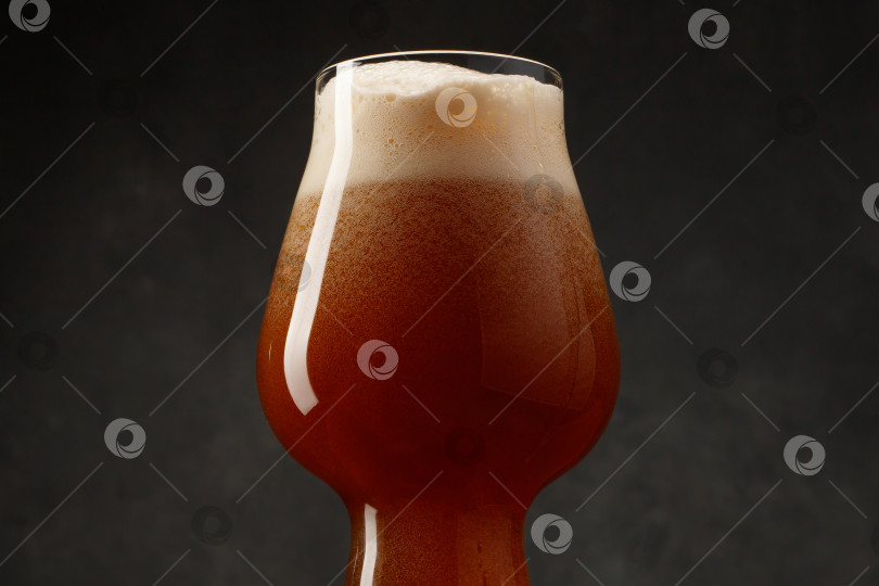 Скачать Деталь бокала, наполненного темным пивом, на темном фоне. фотосток Ozero