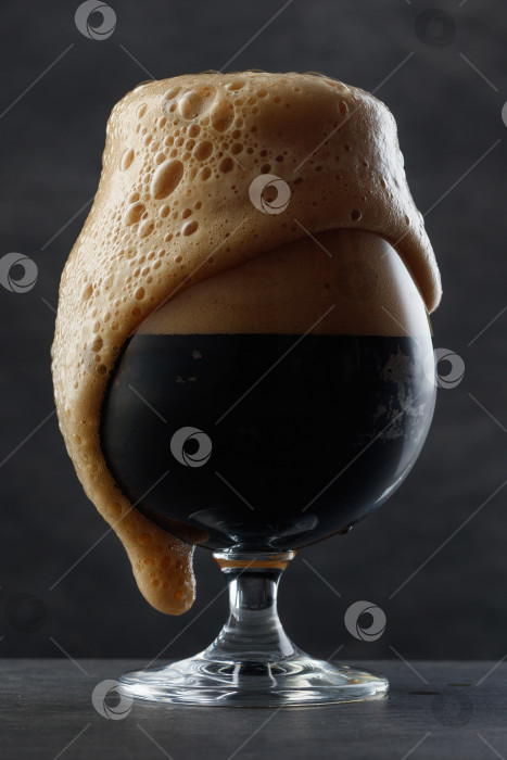 Скачать Деталь темного пива с переливающейся через край головкой пены. фотосток Ozero