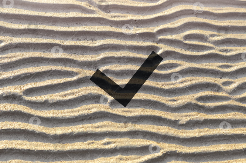 Скачать Черная галочка на фоне поверхности волнистого песка с уникальным природным рисунком. Концепция проверки личности по отпечаткам пальцев фотосток Ozero