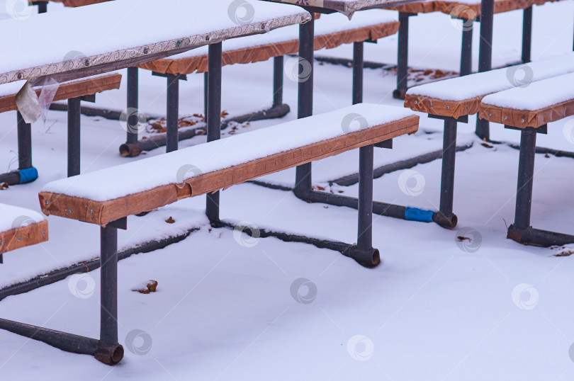 Скачать Зимой столы и скамейки в уличном кафе покрыты снегом. фотосток Ozero
