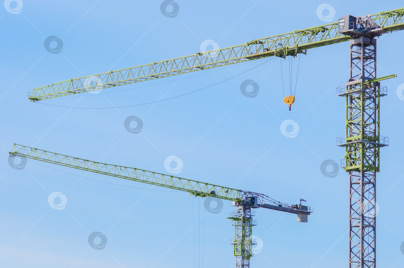 Скачать Два стреловых крана на фоне голубого неба. Крупногабаритная строительная техника. фотосток Ozero