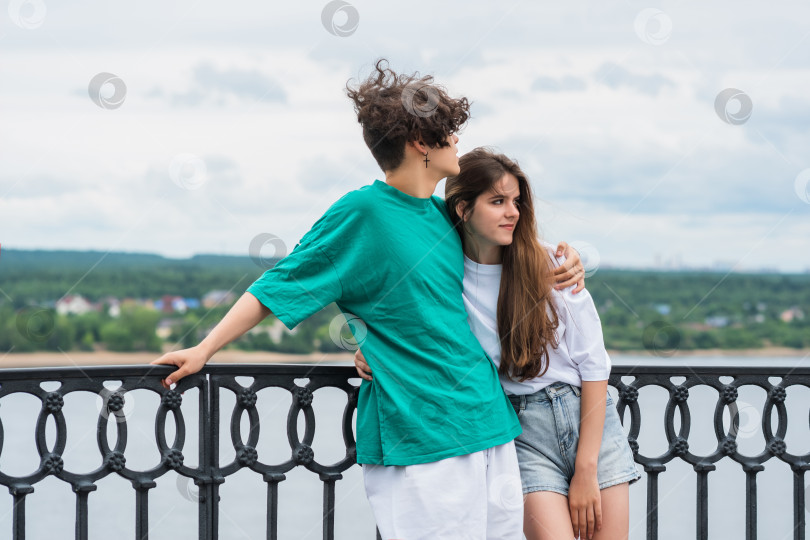 Скачать пара молодых людей обнимается на набережной над рекой фотосток Ozero