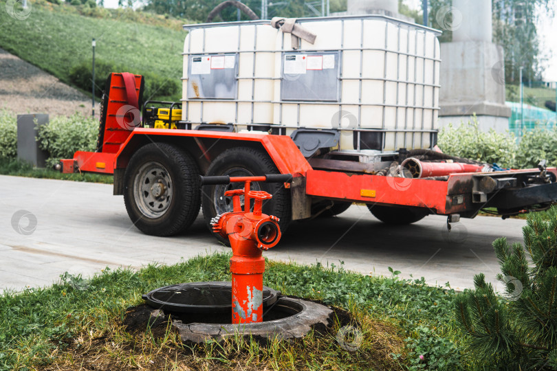 Скачать пожарный гидрант на фоне прицепа в резервуарах для воды для полива растений фотосток Ozero