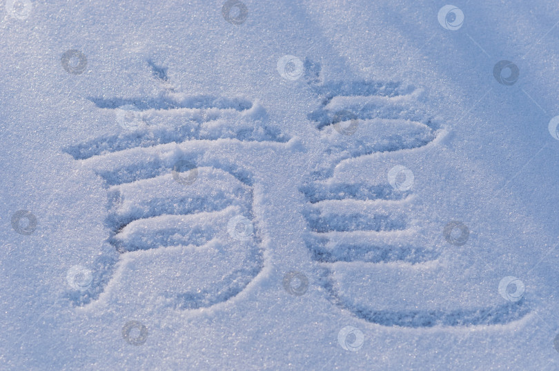 Скачать Китайский иероглиф "дракон" написан палочкой на гладкой снежной поверхности. фотосток Ozero
