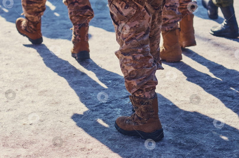 Скачать Ноги солдат в военной форме и армейских ботинках идут по льду навстречу восходу солнца. фотосток Ozero