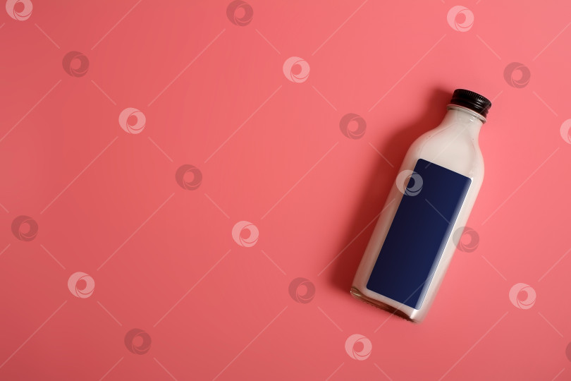 Скачать Стеклянная бутылка с белой жидкостью (молоком, сливками, соусом), выделенная на розовом фоне фотосток Ozero