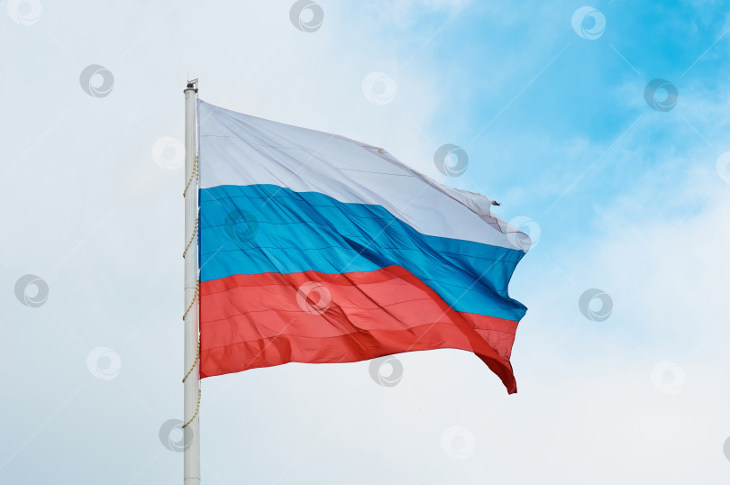Скачать Большой российский флаг крупным планом на фоне облачного неба. фотосток Ozero