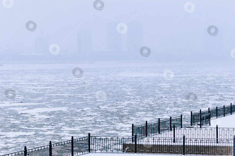 Скачать Snowfall on the embankment of the Amur River during ice drift. Black metal railings. Stair railing covered with snow. No people. Blagoveshchensk, Far East, Russia фотосток Ozero