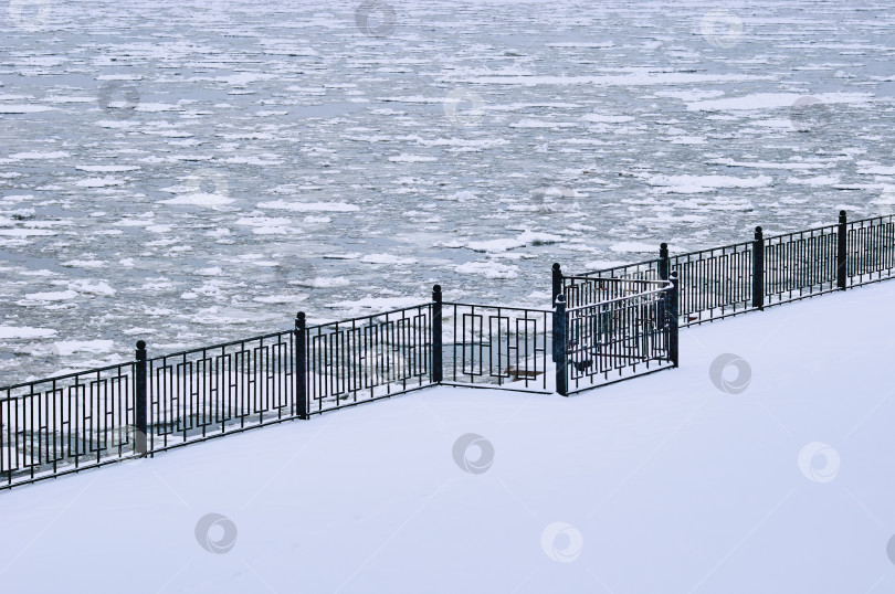 Скачать Snowfall on the embankment of the Amur River during ice drift. Black metal railings. Stair railing covered with snow. No people. Blagoveshchensk, Far East, Russia фотосток Ozero