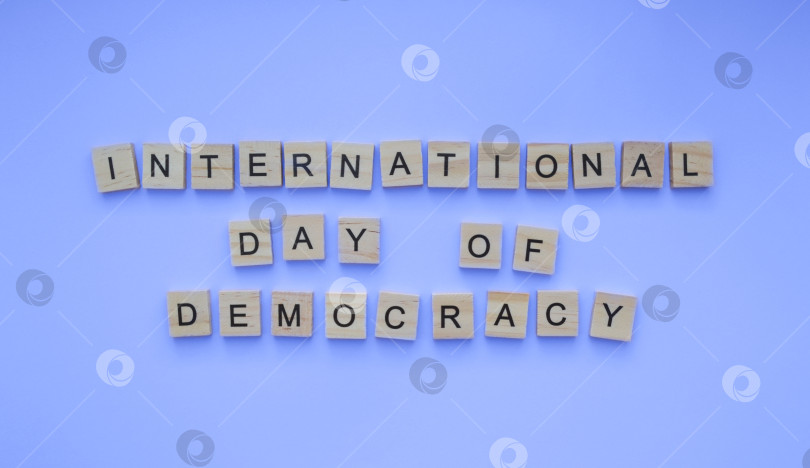 Скачать September 15, International Day of Democracy, minimalistic banner with the inscription in wooden letters on a blue background фотосток Ozero