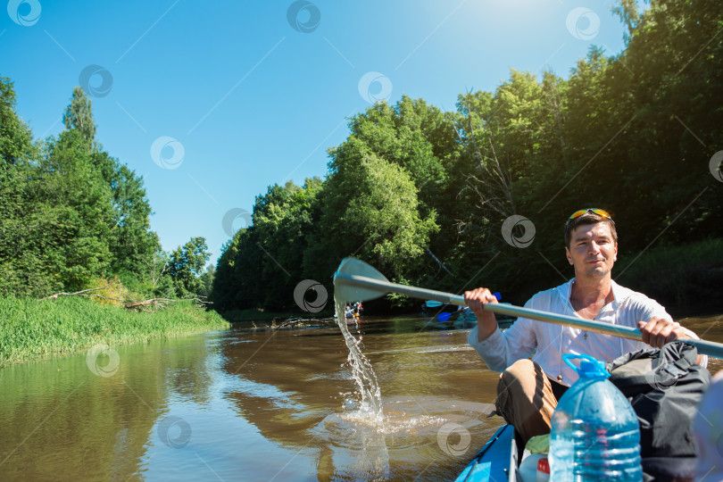 Скачать Мужчина в каяке плывет на весельной лодке по реке, водный поход, летнее приключение. Экологичный и экстремальный туризм, активный и здоровый образ жизни фотосток Ozero