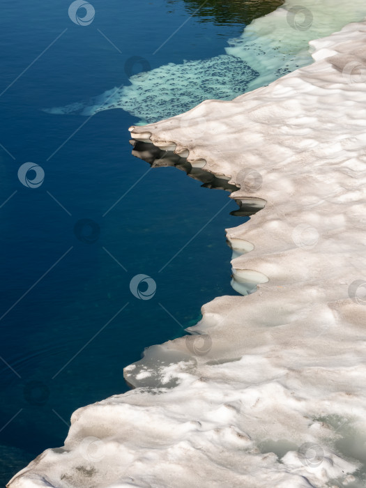 Скачать Impressive ice floe melts on a mountain lake. White iceberg on the blue water. Natural background. Vertical view. фотосток Ozero