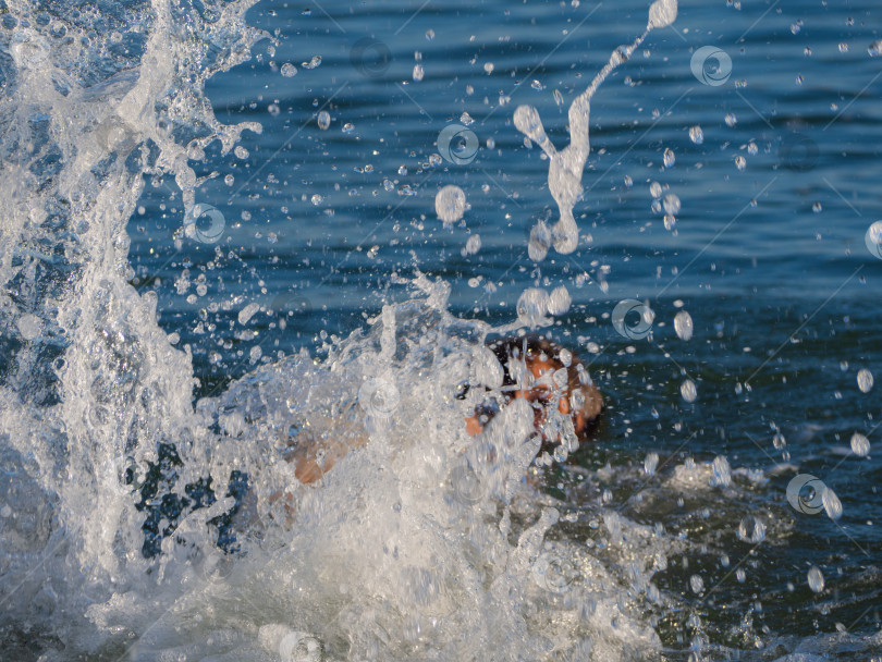 Скачать A close-up of a splash of seawater, big and small drops flying up to the top of the frame. There is room for text on a beautiful blue background. фотосток Ozero