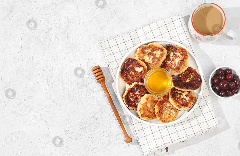 Скачать Fritters with cherries, honey and coffee on a light background. The concept of healthy and natural food. Healthy breakfast with ingredients, food for kids. selective focus, flat lay, top view фотосток Ozero