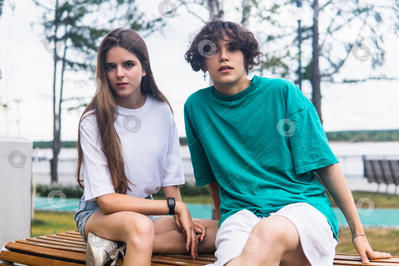 Скачать two young people are sitting on a bench in a coastal park фотосток Ozero