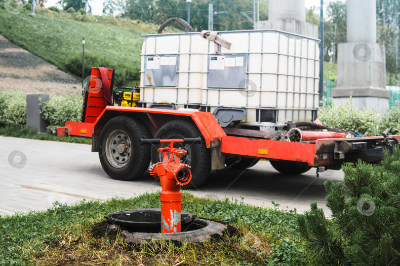 Скачать fire hydrant on the background of a trailer in water tanks for watering plants фотосток Ozero