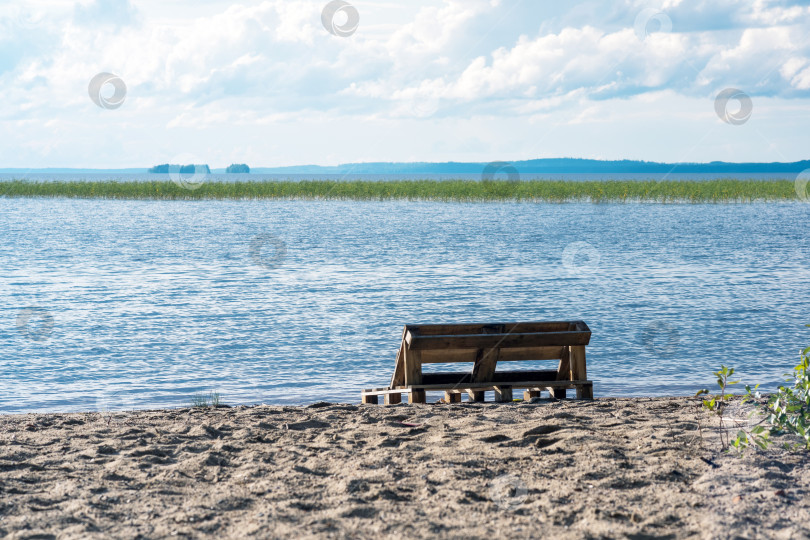 Скачать bench made of old pallets on a sandy shore of a vast lake фотосток Ozero