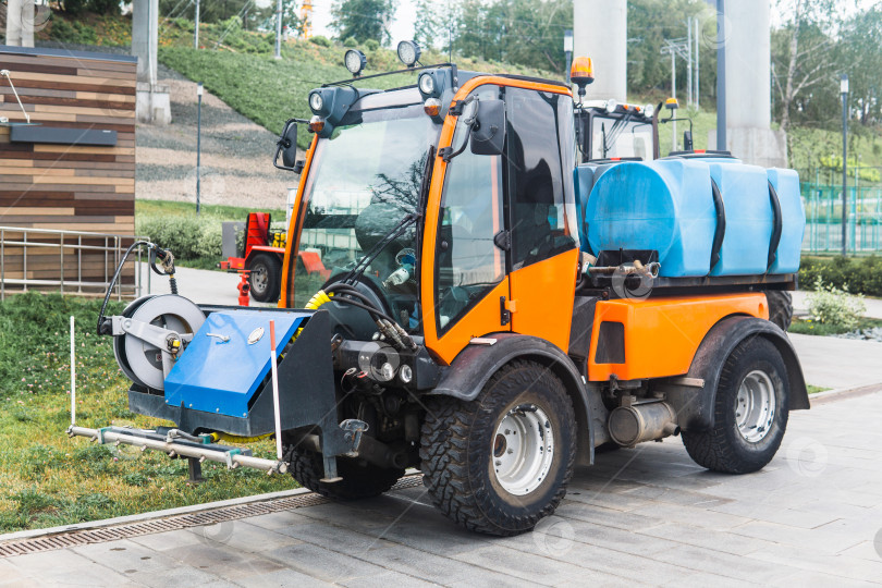 Скачать small tank truck for cleaning paths and watering plants in the city park фотосток Ozero