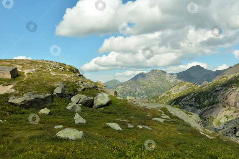 Скачать Gentle rocky slopes of a high mountain before climbing the pass on a sunny summer day. фотосток Ozero