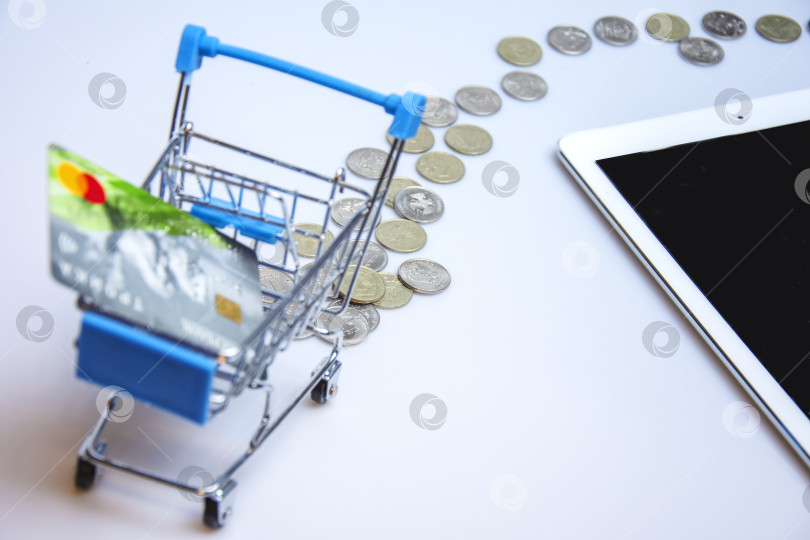 Скачать A supermarket cart with a credit card on the background of a tablet screen with an image of an online store. фотосток Ozero