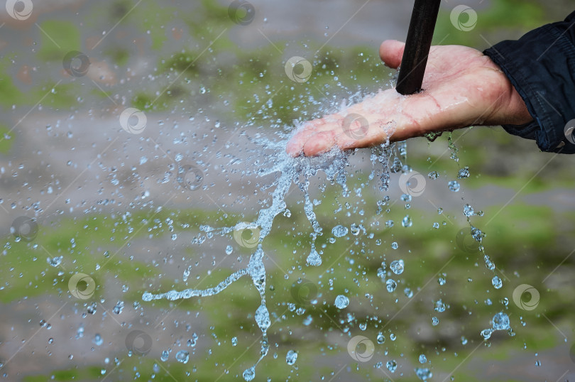 Скачать A jet of water pours onto a man's palm, breaking into splashes. Close up. фотосток Ozero