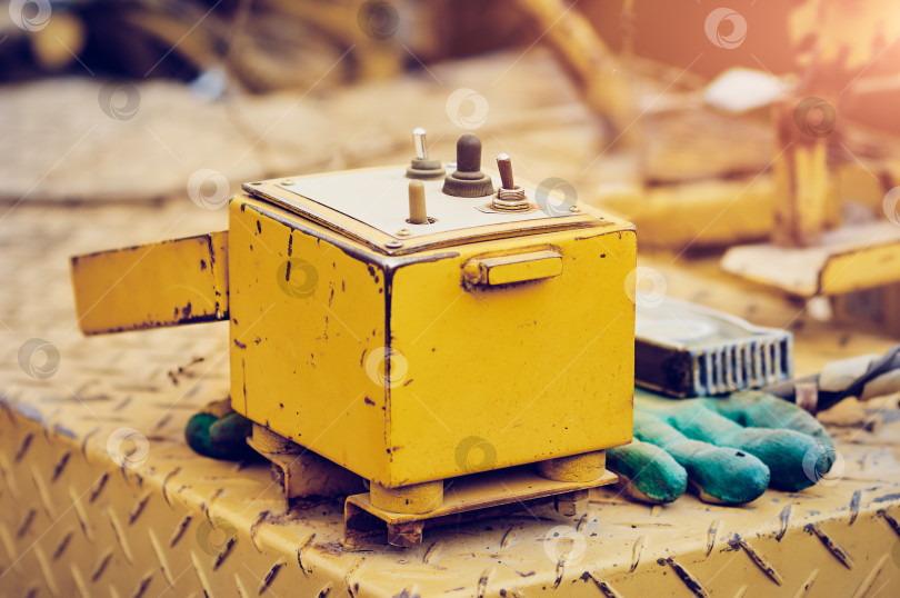 Скачать The equipment control panel of a paver car in a small yellow metal box. Old technological device with traces of corrosion close up. фотосток Ozero