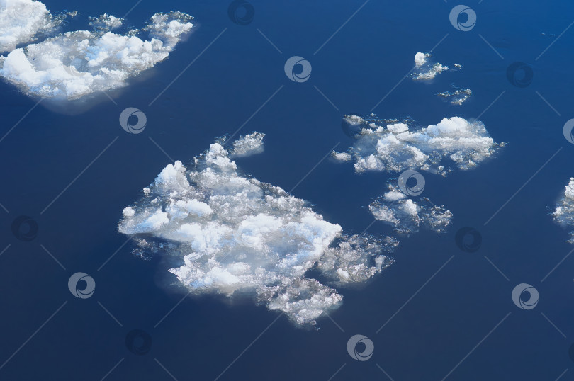 Скачать Ice floes float on the river. Seasonal ice drift. Reflection of the blue sky in the water. фотосток Ozero